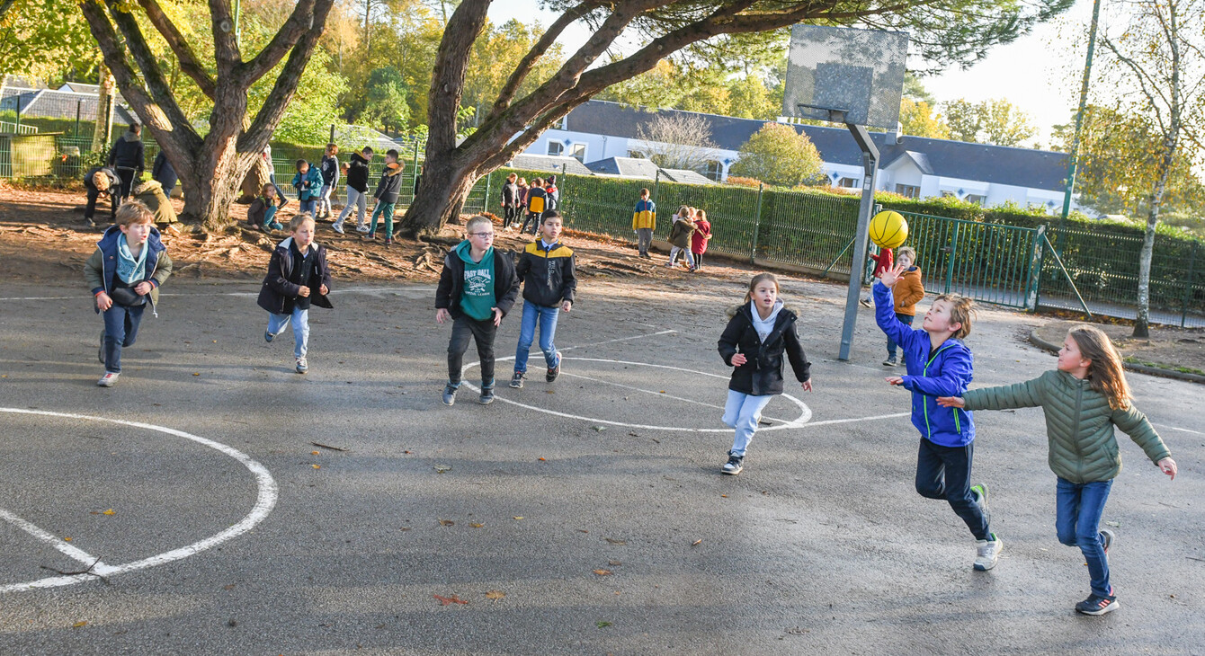 Des enfants jouant au basket-ball dans la cour de récréation